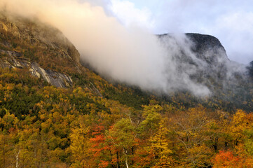 Late autumn afternoon in Franconia Notch State Park, New Hampshire. Low clouds rolling through colorful Franconia Notch illuminated by warm late afternoon sunlight.