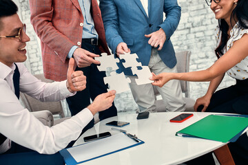 Cropped image of businesspeople joining puzzle pieces in office