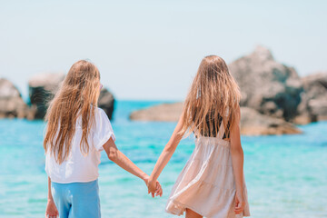 Little happy funny girls have a lot of fun at tropical beach playing together.