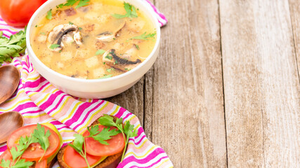Summer mushroom soup with parsley, croutons, tomatoes and vegetarian sandwiches on a wooden background. Copy space.