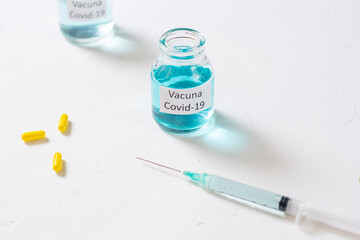 concepto de vacuna del covid 19 con una jeringa y pastillas amarillas en una mesa con espacio para copi