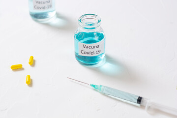 concepto de vacuna del covid 19 con una jeringa y pastillas amarillas en una mesa con espacio para...