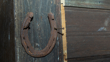 Horseshoe on a brown door background. Horseshoe for good luck. Old wooden door. Space for text. Texture concept.