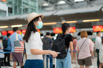 Asian woman traveler wearing mask holding passport at customer check in of airline service counter when traveling by airplane transportation for new normal travel concept..