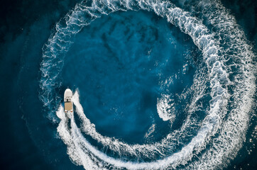 Speed boat in mediterranean sea making a cyrcle from bubbles, aerial view