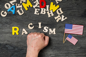 man hand hit wooden letters with racism word
