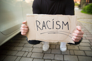 Young man holding racism cardboard in hands