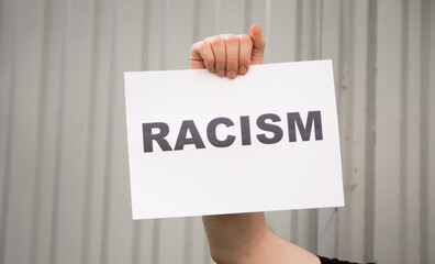 Young man holding racism cardboard in hands