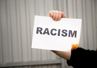 Young man holding racism cardboard in hands