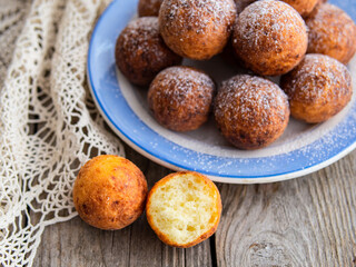 Freshly baked cheese donuts with powdered sugar on the plate on wooden rustic table. The atmosphere of a cozy home breakfast. Close up, copy space.