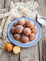 Freshly baked cheese donuts with powdered sugar on the plate on wooden rustic table. The atmosphere of a cozy home breakfast. Close up, copy space.