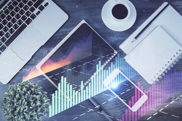 Double exposure of forex chart hologram over desktop with phone. Top view. Mobile trade platform...