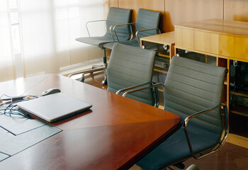 a laptop closed on the wooden table of a corporate board