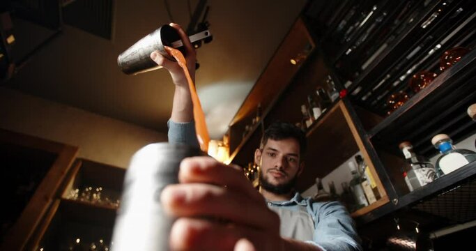 Authentic professional caucasian bartender creating a cocktail drink. Experienced barman pouring alcohol beverage in shaker - food and drink concept close up 4k footage