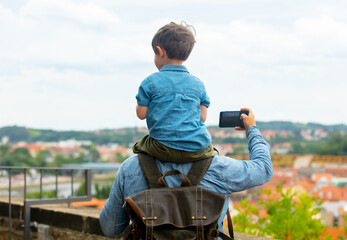 child sits on his father's shoulders while walking through the streets of the old city