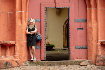 woman stay near old red doors in roman style in Europe