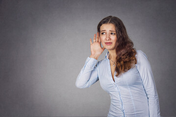 Curious woman with hand to ear carefully listening to gossip con