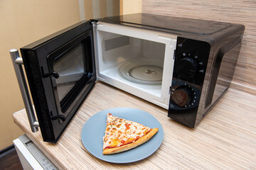 Plate with slice of pizza next to the microwave