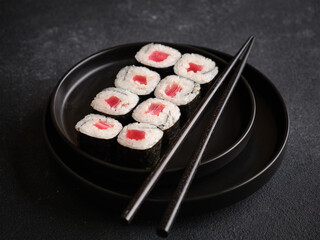Rolls with tuna on a black plate.