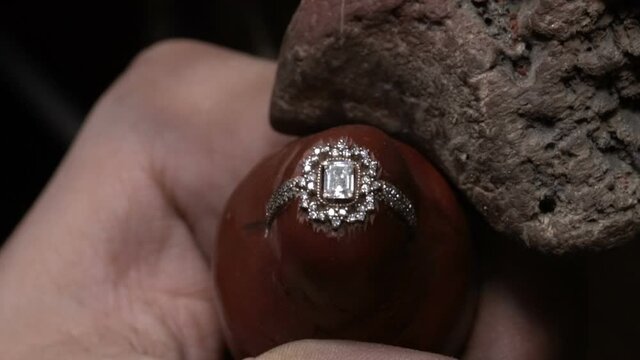 craftsman making jewelery in his workshop. handmade diamond jewelery. close up shooting in jeweler master workshop. putting emerald diamond gem. roze gold diamond ring. close u? macro shooting