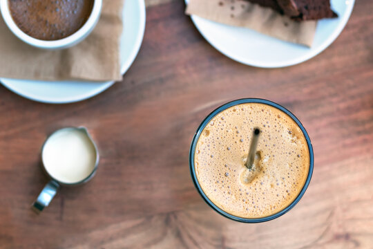 Top view of a greek cold coffee, freddo - frape espresso placed on a wooden table outdoors.