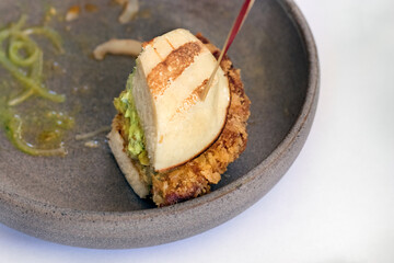 Bun Fried chicken burger with green sauce a plate, gourmet dish.
