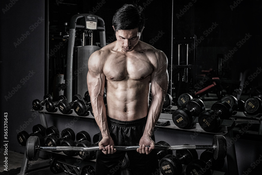 Wall mural strong fitness man doing arm workout with barbells in the gym