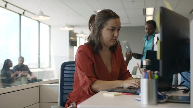 Coding at a technology company. A young woman programer is hard at work at a tech company creating the next big app. Shot in slow-motion and in 4k. 