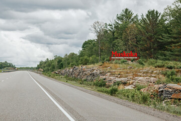 Canadian Ontario touristic destination place landmark. Red word sign Muskoka on empty road in...