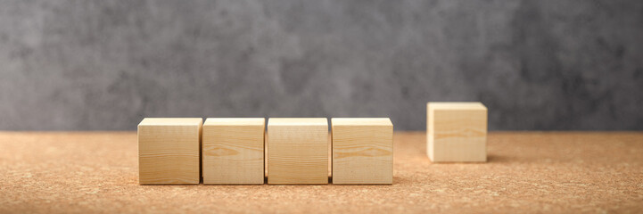 empty wooden cubes for own messages and icons on cork surface in front of a concrete wall