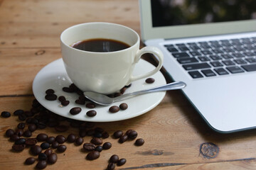 Coffee cups and coffee beans Placed next to the laptop on a wooden table