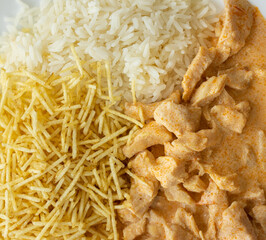 Strogonoff servido em prato branco com batata palha e arroz branco. Comida gostosa.