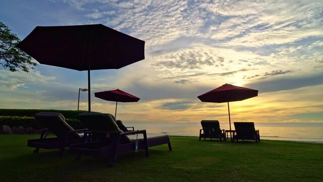 Umbrella with chair with sea beach background and sunrise in morning - vacation and holiday concept