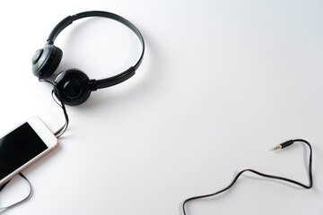 Top view of black headphones on white or pastel color background.