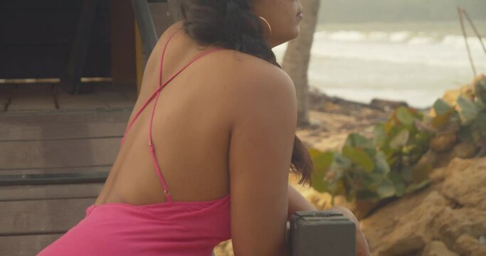 Revealing shot of a female model standing in a lifeguard booth looking at the waves crashing on the shoreline