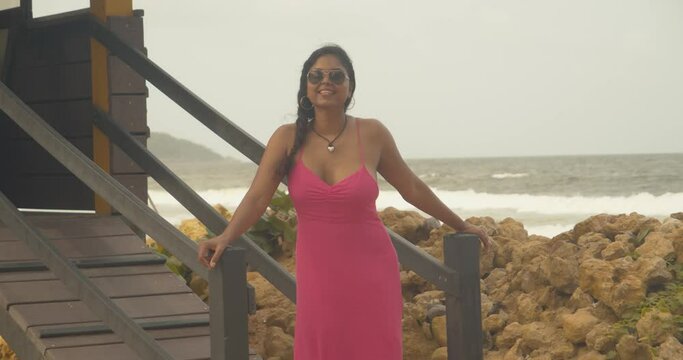 A sexy female acting as a lifeguard with waves crashing at the shoreline in the background