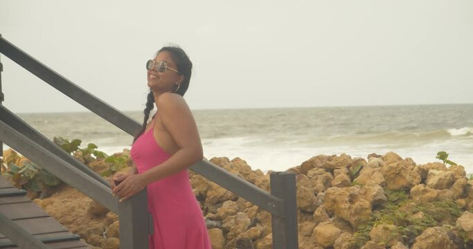 A sexy east indian model stands at the entrance to a lifeguard booth while laughing and having a good time