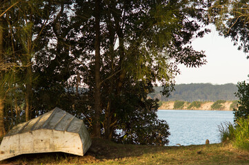 Obraz premium Upside Down Rowboat on the shore of a peaceful river 