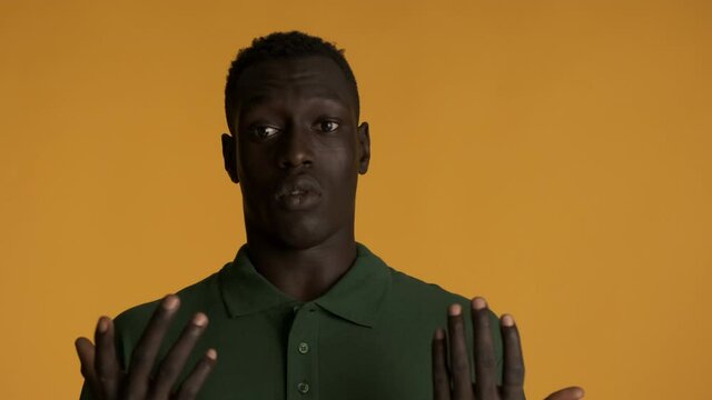Young amazed African American man scaredly looking in camera showing not me gesture over colorful background. Shocked expression