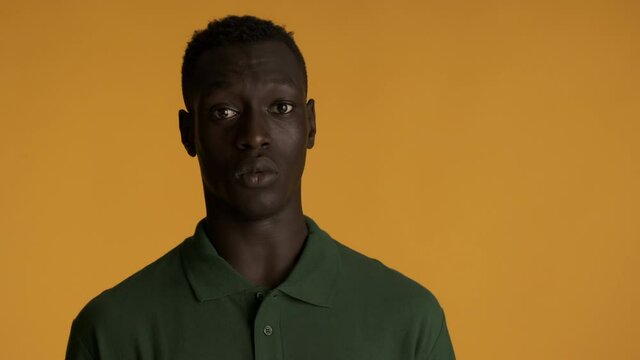 Young shocked African American man scaredly looking in camera over colorful background. It's not me expression