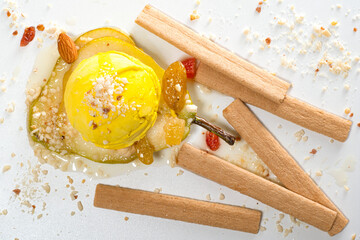 Lemon ice cream on a slice of pear poured with syrup with dried berries, nuts and cookies on a...