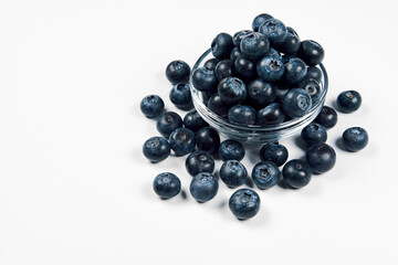 Freshly juicy picked blueberries in glass bowl isolated on white background. Top view. Selective focus. Free text space. Concept of healthy eating and nutrition..