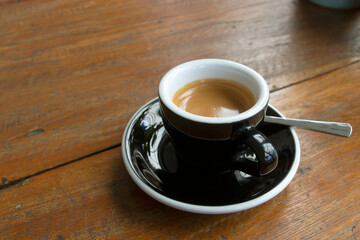 Cup of black coffee on the wooden table in cafe.