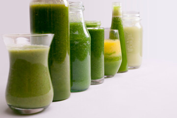 Blended green smoothie with ingredients on white background.
