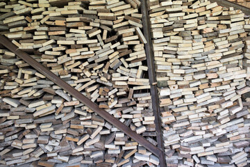 A large pile of cut wooden boards arranged along a wall