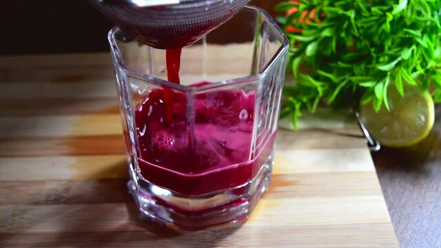 Red beetroot juice being poured into the glass by sieve. Red beetroot juice pouring into the glass. Red juice close view. 