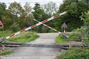 Railway crossing with a opening barrier or gates and signalling in the spot where country road...