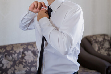 a man puts on a tie in front of a mirror