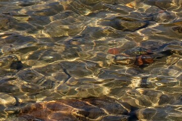 lake surface with small waves, stones below the surface