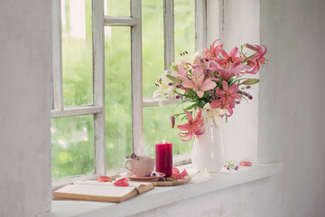 cup of tea and summer flowers on vintage windowsiil